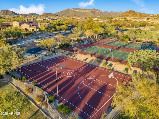 view of sport court featuring a tennis court, community basketball court, a mountain view, and fence