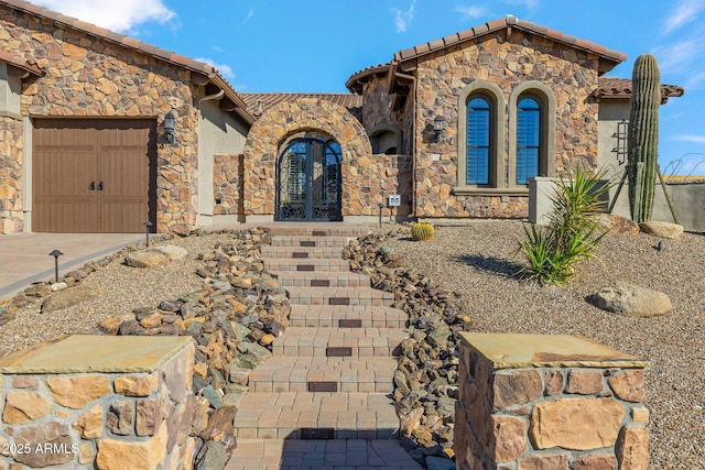 mediterranean / spanish house with stucco siding, concrete driveway, french doors, a garage, and a tiled roof