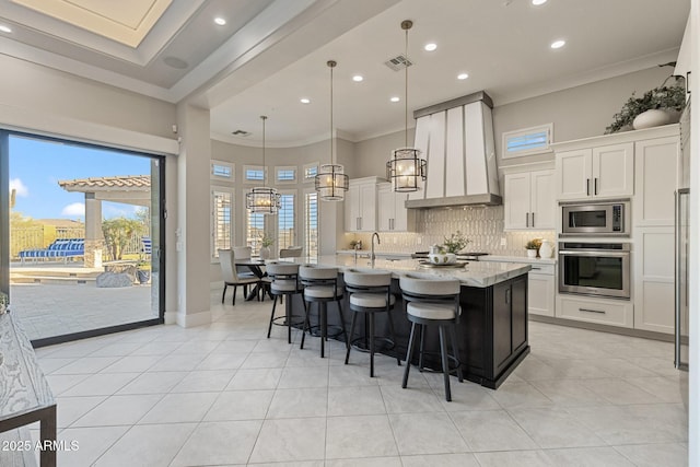 kitchen featuring visible vents, backsplash, premium range hood, ornamental molding, and stainless steel appliances