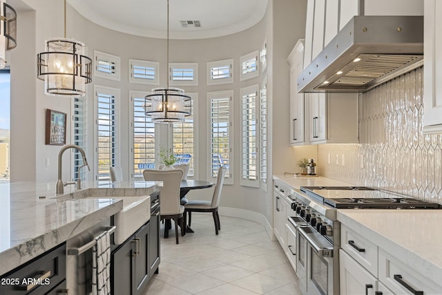 kitchen featuring double oven range, a sink, hanging light fixtures, under cabinet range hood, and crown molding