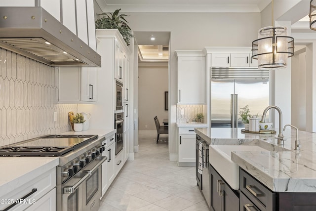 kitchen with white cabinets, built in appliances, under cabinet range hood, and ornamental molding