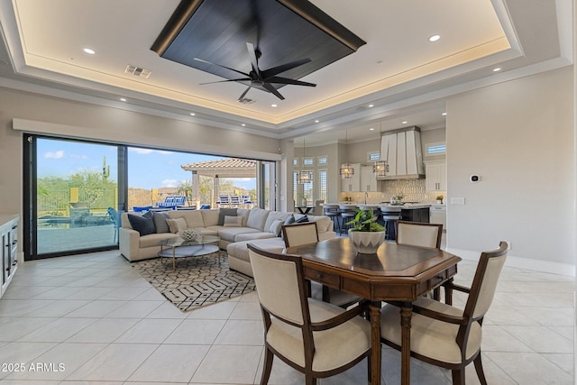 dining area with ceiling fan, a tray ceiling, baseboards, and light tile patterned flooring