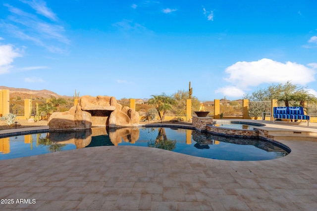 view of swimming pool with a patio area, a pool with connected hot tub, and fence