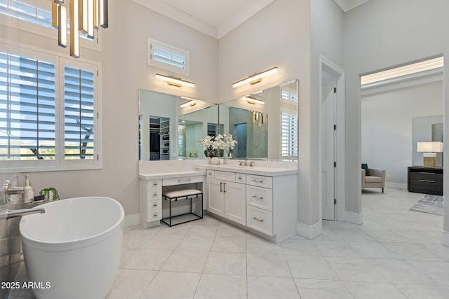 bathroom featuring tile patterned floors, crown molding, baseboards, a soaking tub, and vanity