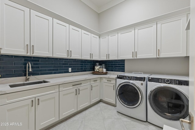 clothes washing area with light tile patterned floors, washing machine and clothes dryer, cabinet space, a sink, and crown molding