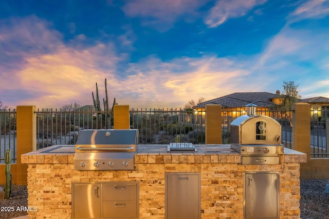 view of patio with grilling area, an outdoor kitchen, and fence