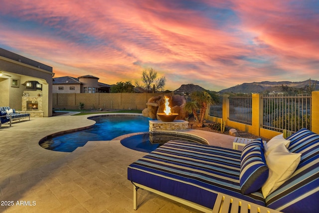 view of swimming pool featuring an outdoor living space with a fireplace, a fenced backyard, a mountain view, a fenced in pool, and a patio area