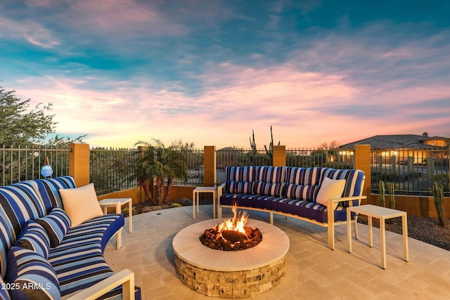 patio terrace at dusk featuring an outdoor living space with a fire pit and fence