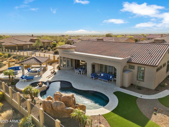 rear view of house with an outdoor living space with a fire pit, a patio, a fenced backyard, and stucco siding