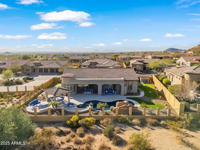 rear view of property featuring a residential view, a tile roof, stucco siding, a fenced backyard, and outdoor dining space