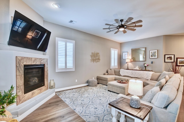 living room with wood-type flooring, ceiling fan, and a fireplace