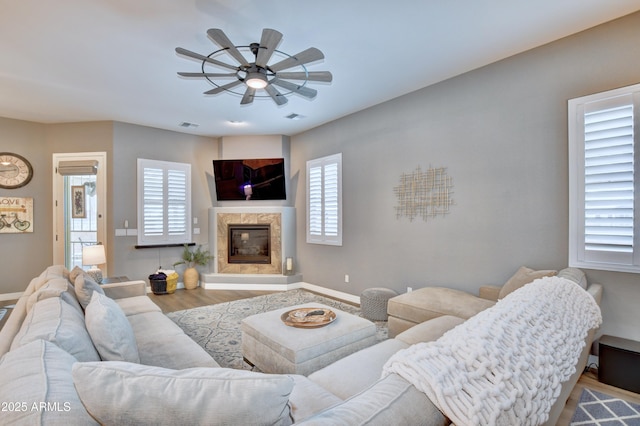 living room featuring hardwood / wood-style flooring, ceiling fan, and a fireplace