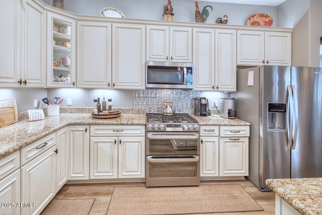 kitchen featuring appliances with stainless steel finishes, light stone countertops, and white cabinets