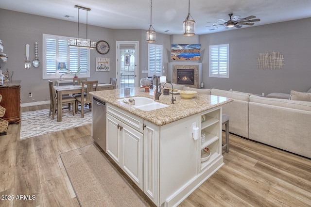 kitchen with sink, decorative light fixtures, dishwasher, a kitchen island with sink, and white cabinets