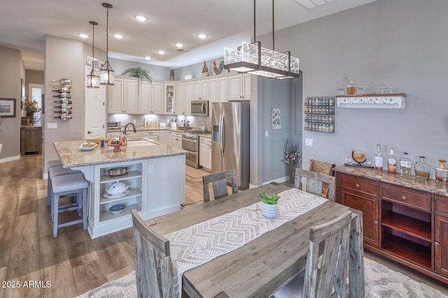 kitchen featuring stainless steel appliances, an island with sink, sink, and pendant lighting