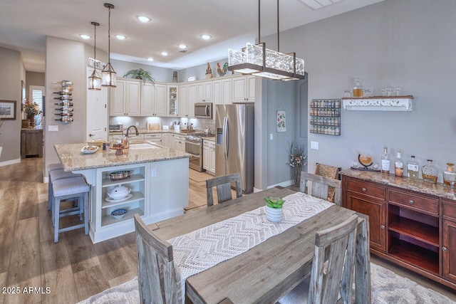 kitchen featuring pendant lighting, appliances with stainless steel finishes, sink, and an island with sink