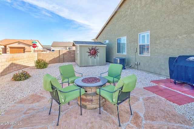 view of patio featuring cooling unit, a storage shed, and a fire pit