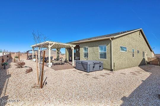 rear view of property with a pergola, a patio area, and a hot tub