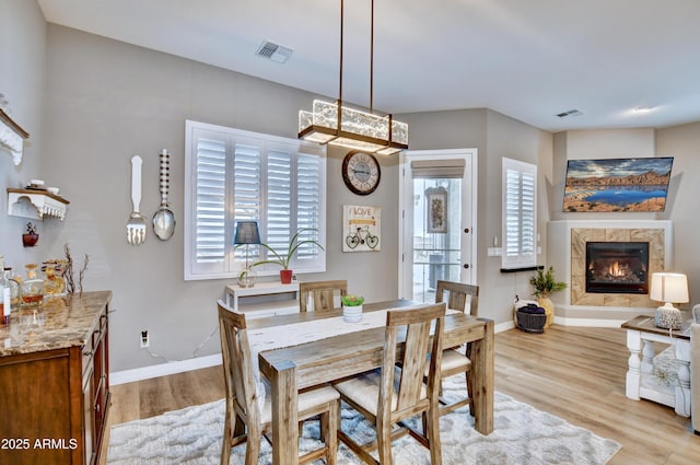 dining room featuring a premium fireplace and light hardwood / wood-style flooring