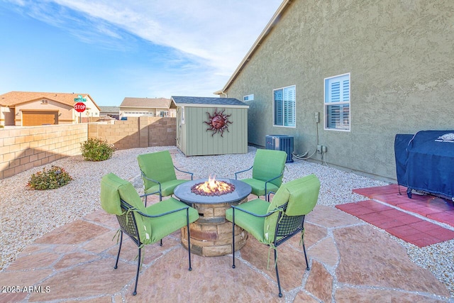 view of patio / terrace featuring a storage shed, a fire pit, and central air condition unit