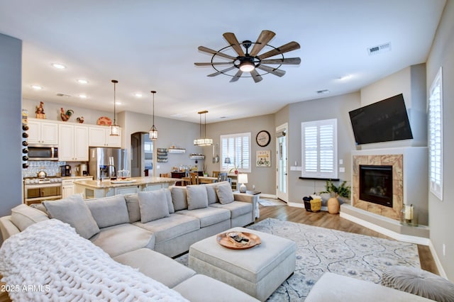 living room featuring a fireplace, ceiling fan, and light wood-type flooring