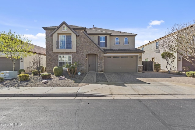 traditional-style house featuring stucco siding, driveway, stone siding, fence, and an attached garage