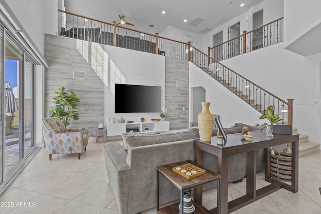 living room with a ceiling fan, a high ceiling, recessed lighting, tile patterned flooring, and stairs