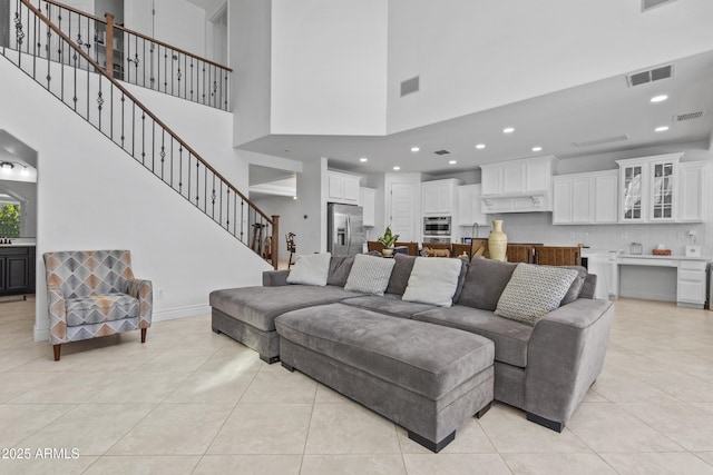 living area featuring stairway, light tile patterned floors, and visible vents