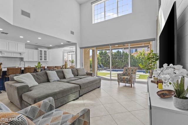 living area with light tile patterned floors, visible vents, recessed lighting, and a high ceiling