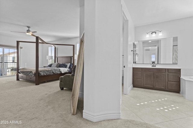 bedroom with light carpet, light tile patterned floors, ensuite bathroom, and a sink