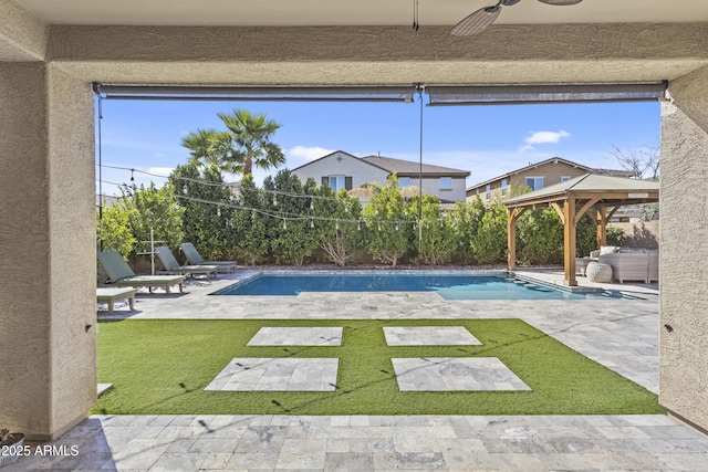 view of pool with a gazebo, a patio, a fenced backyard, and ceiling fan