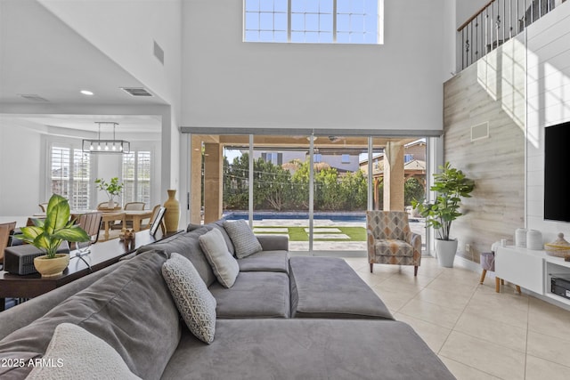 living area featuring tile patterned floors, visible vents, and a towering ceiling