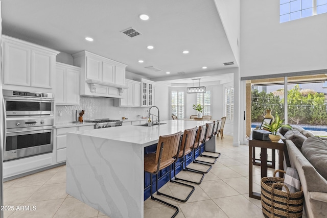 kitchen with light tile patterned floors, visible vents, double oven, and a sink