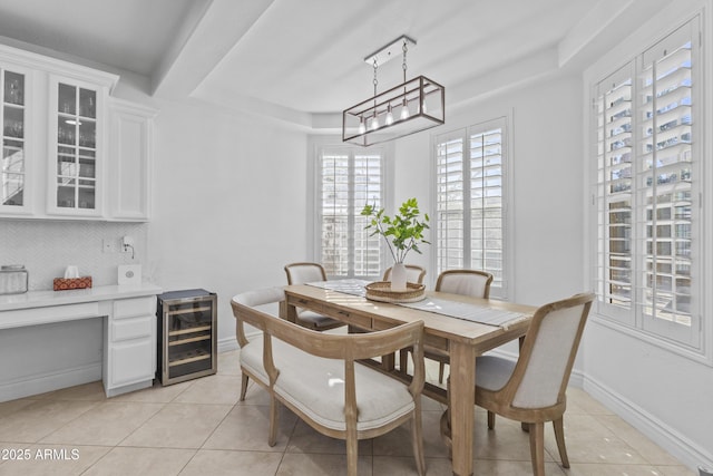 dining area featuring light tile patterned floors, a tray ceiling, baseboards, and beverage cooler