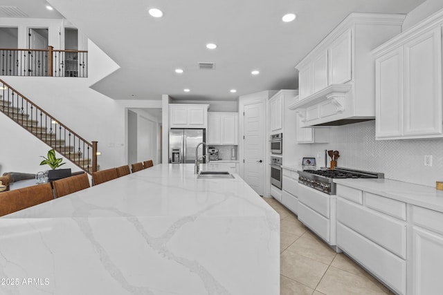 kitchen with visible vents, appliances with stainless steel finishes, light tile patterned flooring, white cabinets, and a sink