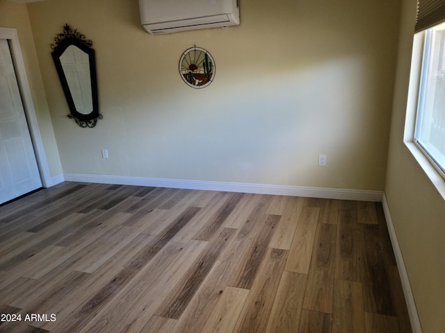 empty room with a wall mounted air conditioner and hardwood / wood-style floors