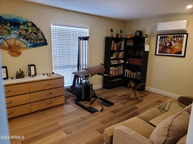 living area with a wall mounted AC and light hardwood / wood-style floors