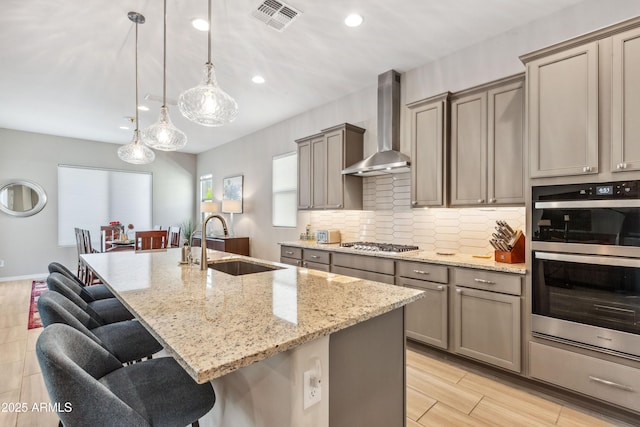 19045 N 269th Dr, Buckeye, AZ 85396 - kitchen with wall chimney range hood, a sink, appliances with stainless steel finishes, a breakfast bar, and tasteful backsplash