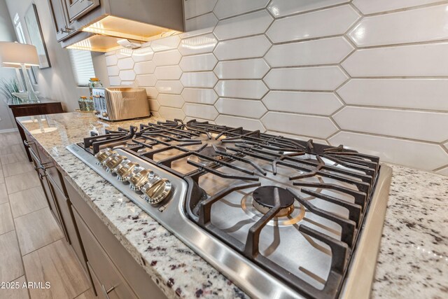 19045 N 269th Dr, Buckeye, AZ 85396 - kitchen view of stainless steel gas cooktop, backsplash, and light stone counters