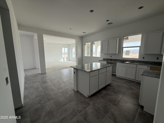 kitchen with stone counters, visible vents, dark tile patterned flooring, and a center island