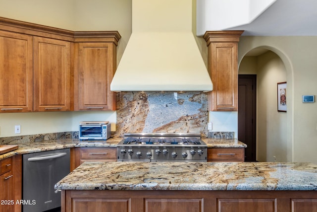 kitchen with tasteful backsplash, stove, stainless steel dishwasher, light stone counters, and custom range hood