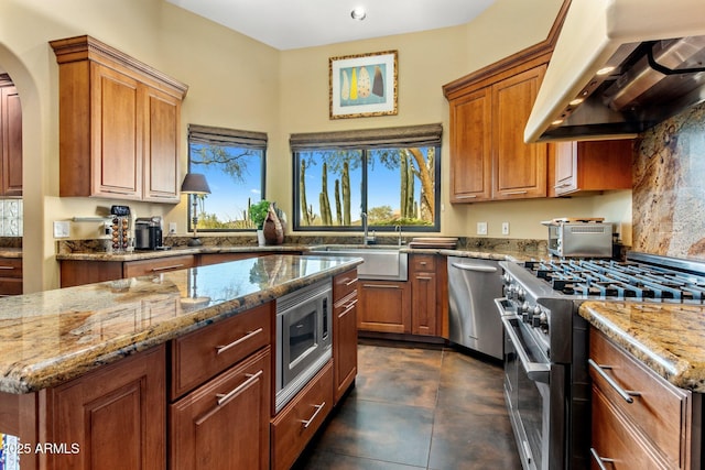 kitchen featuring sink, appliances with stainless steel finishes, a center island, extractor fan, and light stone countertops