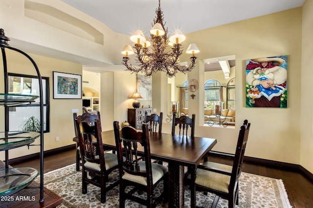 dining space with dark wood-type flooring and an inviting chandelier