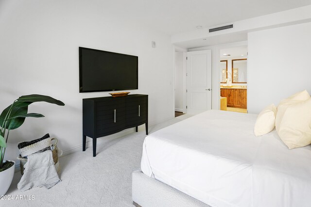 bedroom with light carpet and ensuite bath