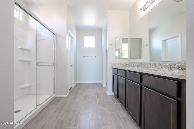 bathroom with vanity, a shower with shower door, and wood-type flooring