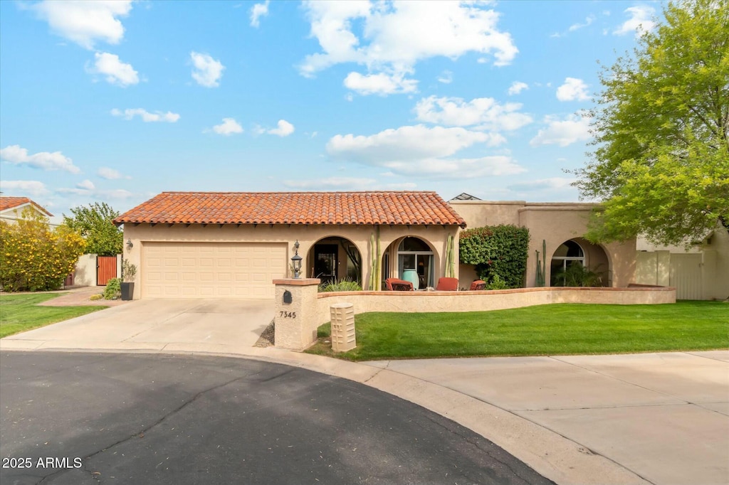 mediterranean / spanish home with a tiled roof, stucco siding, a front yard, an attached garage, and concrete driveway