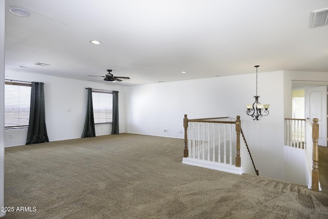 carpeted empty room with ceiling fan with notable chandelier