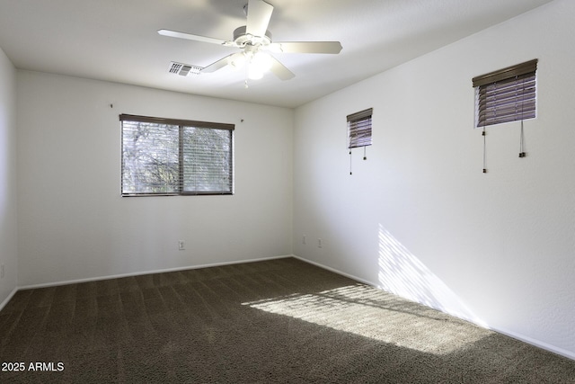 unfurnished room with dark colored carpet and ceiling fan