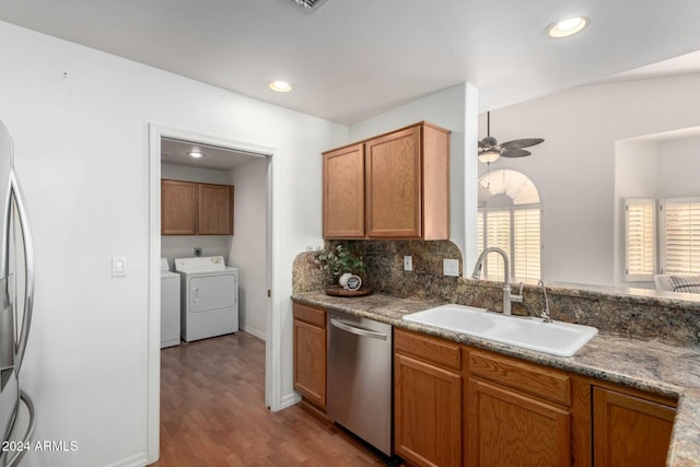 kitchen featuring sink, dishwasher, washer and dryer, stone countertops, and light wood-type flooring