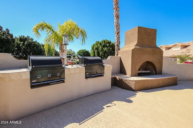 view of patio with a tiled fireplace, exterior kitchen, and area for grilling